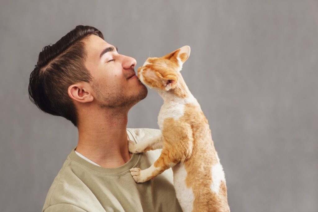 A man is kissing his Devon Rex cat