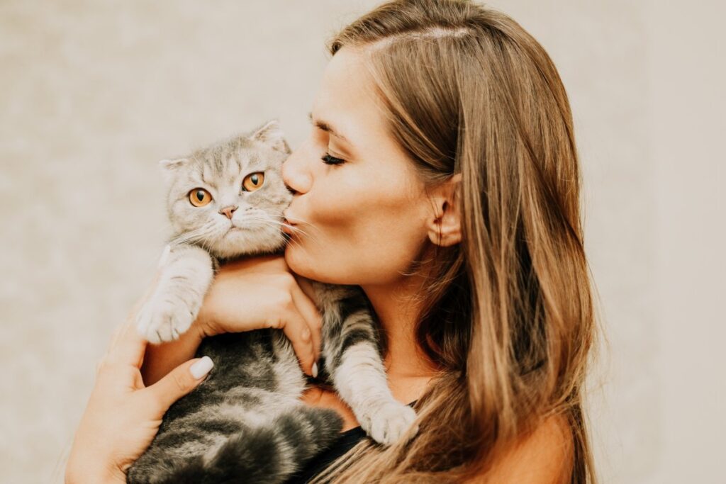 Attractive young woman with long hair embracing her cat with smile