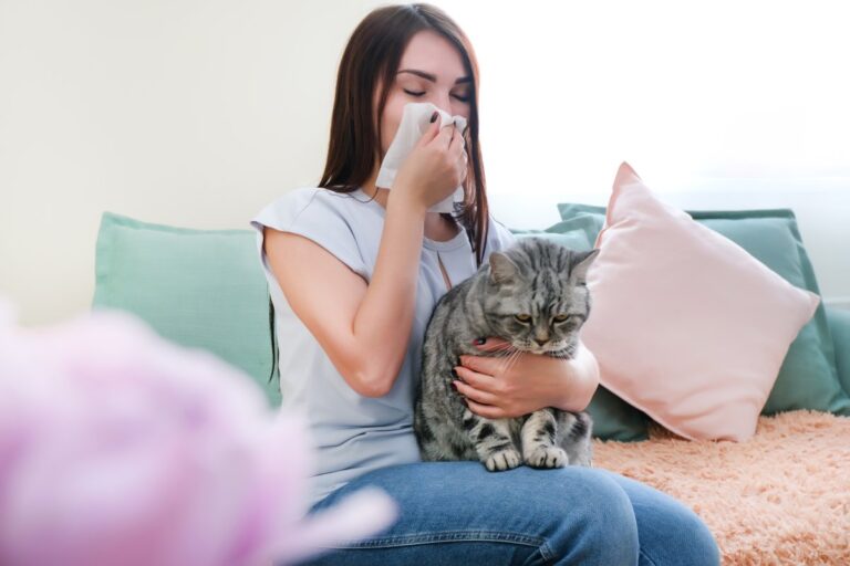 Young woman sneezing from cat allergy
