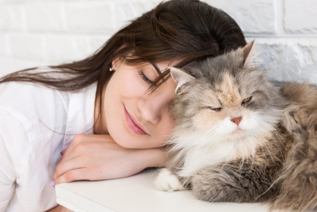 Young woman headbutting her cat