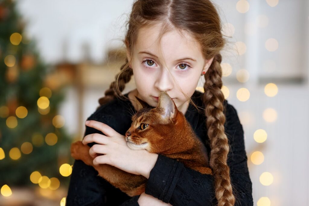 A pretty girl is hugging her cute Abyssinian cat