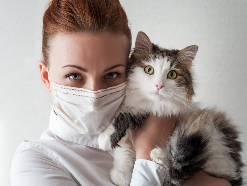 A woman with medical mask is holding her cat