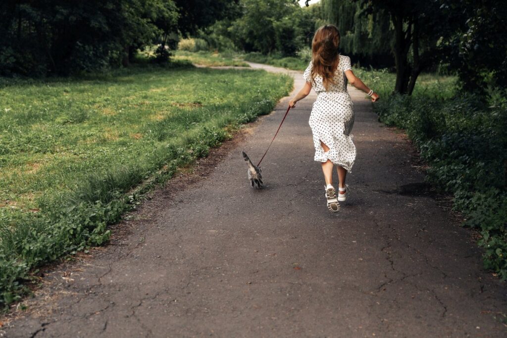 Woman running with her cat in the park
