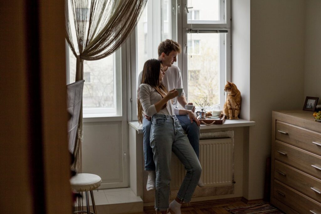 A happy couple is enjoying breakfast with their cat besides